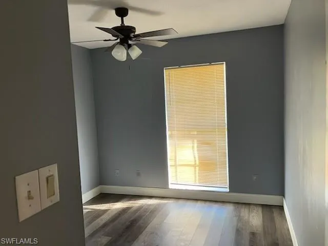 Spare room featuring a ceiling fan, wood finished floors, and baseboards