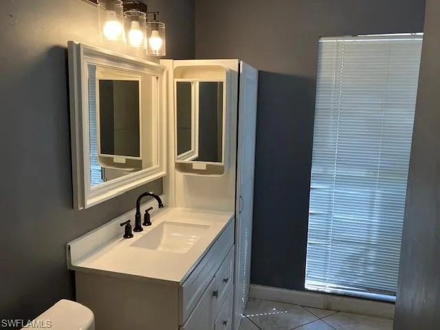 Bathroom with baseboards, toilet, vanity, and tile patterned flooring