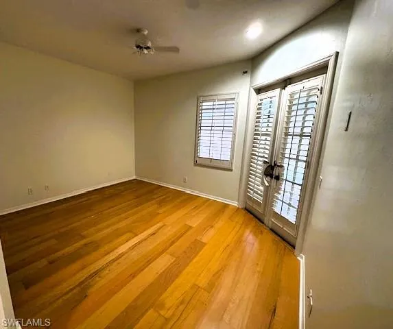 Empty room with french doors, light wood-type flooring, and ceiling fan