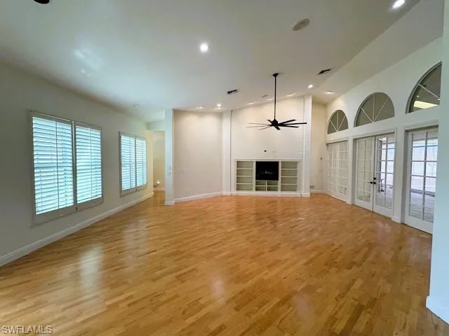 Unfurnished living room featuring ceiling fan, light hardwood / wood-style flooring, and french doors