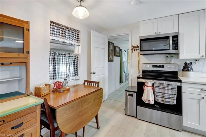 Kitchen with stainless steel appliances, white cabinetry, light countertops, and light wood-style flooring