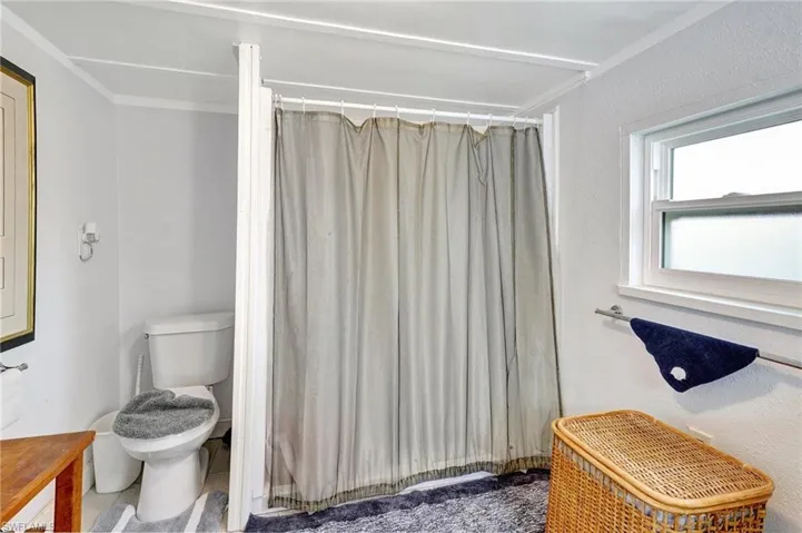 Full bath with toilet, a shower with curtain, and crown molding