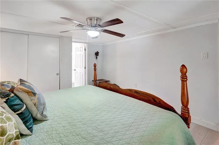Bedroom featuring baseboards, a closet, a ceiling fan, light wood-type flooring, and ornamental molding