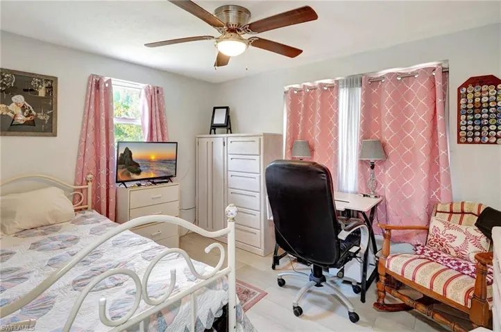 Bedroom with an office area, light wood-type flooring, and ceiling fan