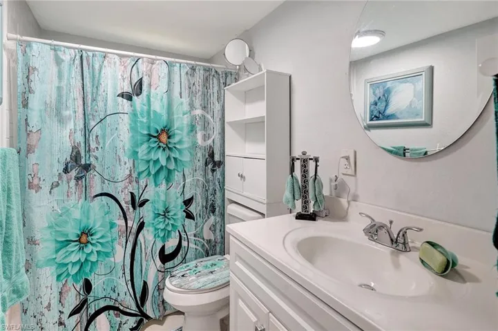 Bathroom featuring toilet, vanity, and a shower with shower curtain