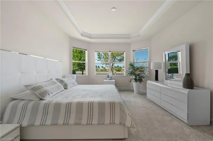 Carpeted bedroom featuring ornamental molding and a raised ceiling