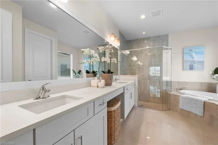 Bathroom featuring double vanity, a garden tub, a stall shower, and healthy amount of natural light