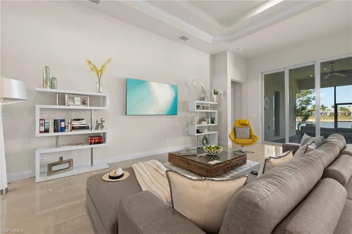 Living area with a ceiling fan, a tray ceiling, and crown molding