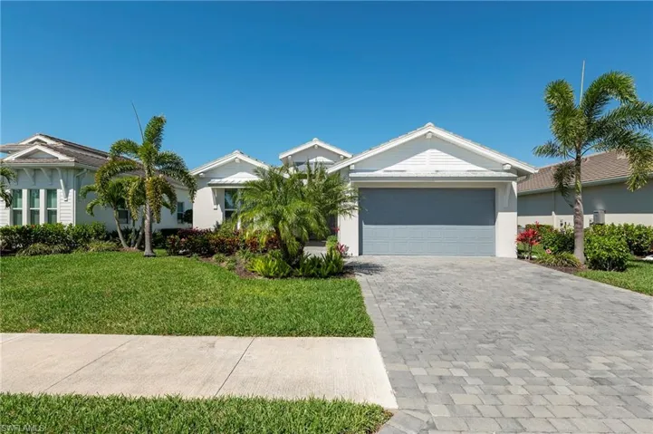 Single story home with a front lawn, decorative driveway, an attached garage, and stucco siding