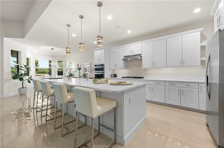 Kitchen with a kitchen island with sink, a kitchen breakfast bar, hanging light fixtures, stainless steel appliances, and recessed lighting