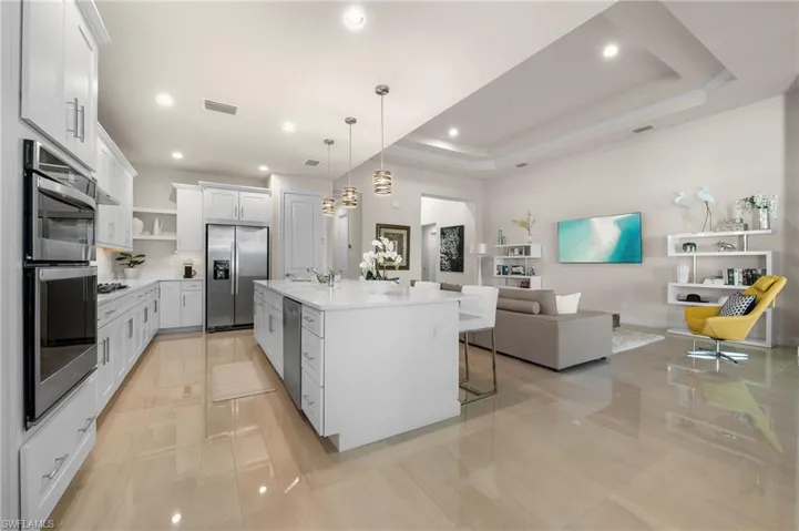 Kitchen with a kitchen bar, white cabinetry, pendant lighting, open shelves, and open floor plan