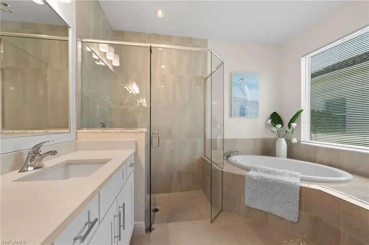 Bathroom featuring vanity, a shower stall, a garden tub, light tile patterned floors, and recessed lighting