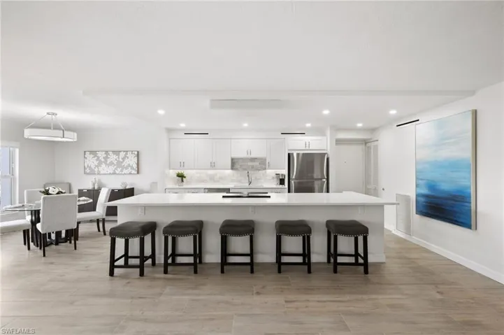 Kitchen with stainless steel refrigerator, decorative light fixtures, a breakfast bar area, and white cabinets
