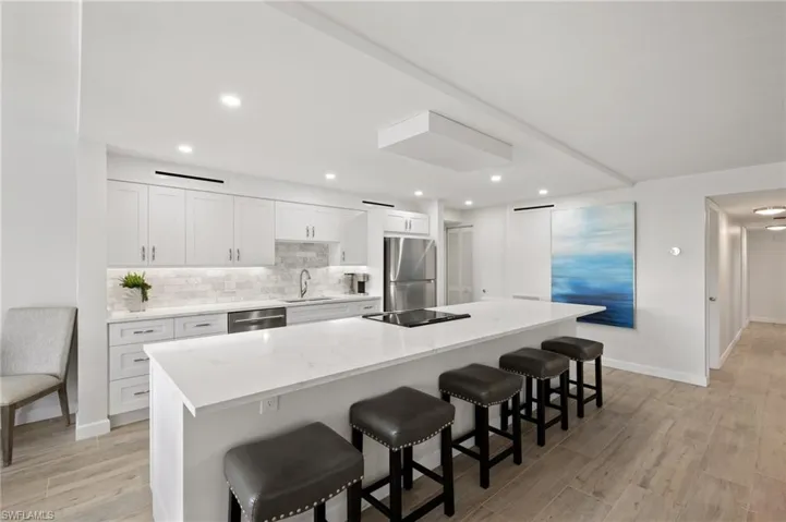 Kitchen featuring a center island, a breakfast bar area, white cabinetry, light hardwood / wood-style flooring, and stainless steel appliances