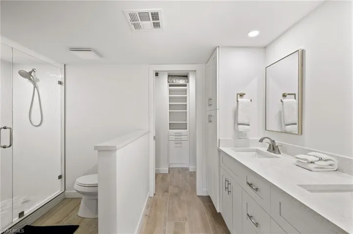 Bathroom featuring wood-type flooring, vanity, toilet, and an enclosed shower