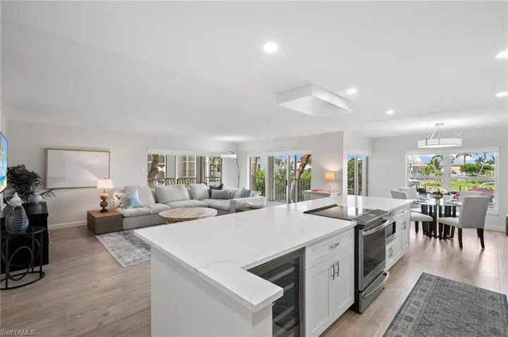 Kitchen with light hardwood / wood-style flooring, wine cooler, white cabinetry, and plenty of natural light