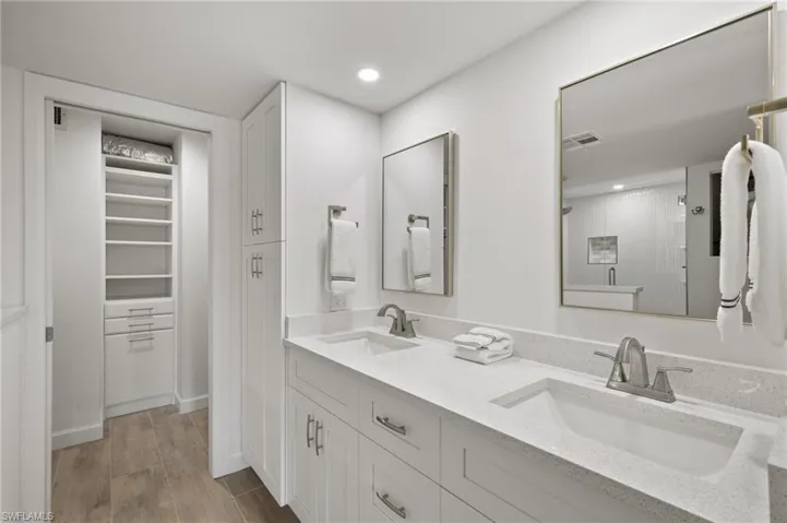 Bathroom featuring walk in shower, vanity, and wood-type flooring