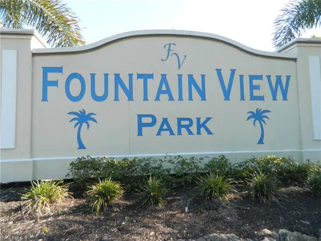Stucco-finish monument sign featuring decorative palm tree iconography and low-profile landscaping