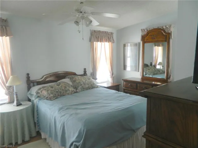 Bedroom featuring a white ceiling fan with integrated lighting and multi-pane windows