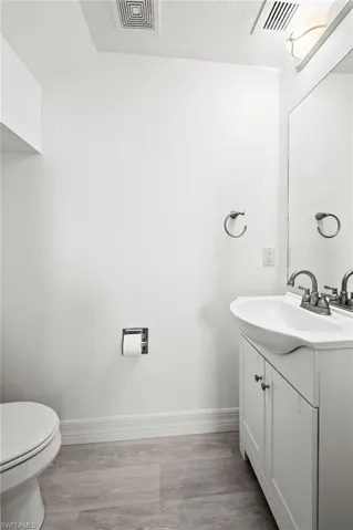 Bathroom with baseboards, visible vents, wood finished floors, and vanity
