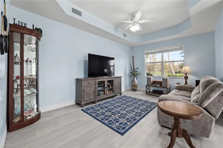 Living room with baseboards, ceiling fan, wood finished floors, and a raised ceiling