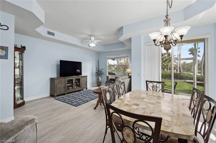 Dining area featuring baseboards, visible vents, light wood-style floors, and a raised ceiling