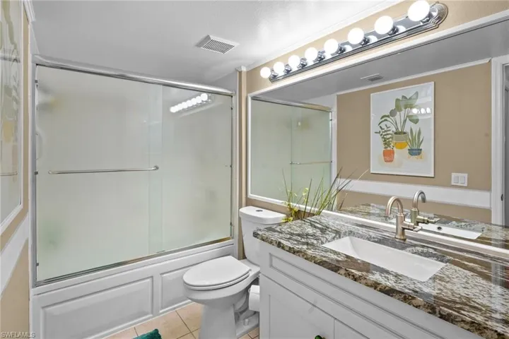 Full bathroom with enclosed tub / shower combo, vanity, and light tile patterned floors