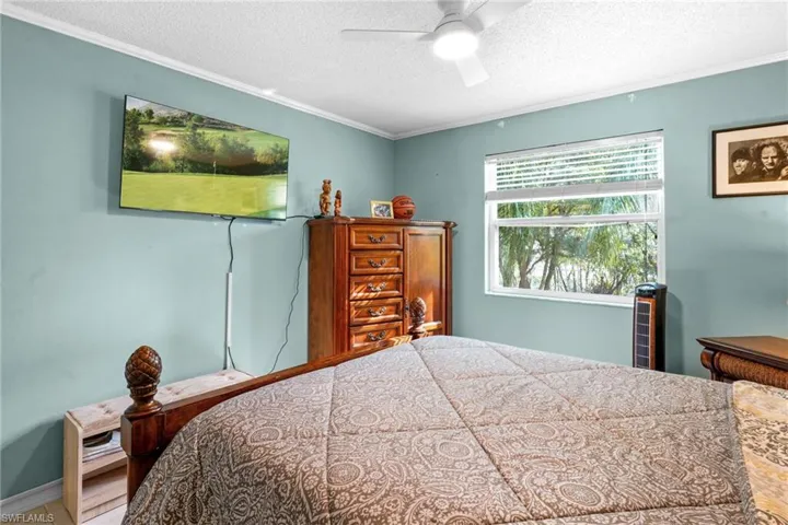 Bedroom featuring a textured ceiling, crown molding, and ceiling fan