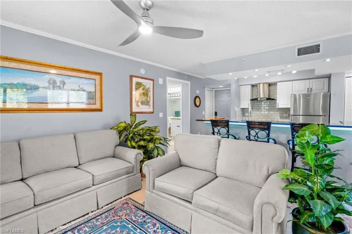 Living area featuring crown molding, a textured ceiling, and a ceiling fan