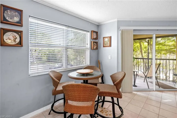 Dining room featuring light tile patterned floors, a textured ceiling, and ornamental molding