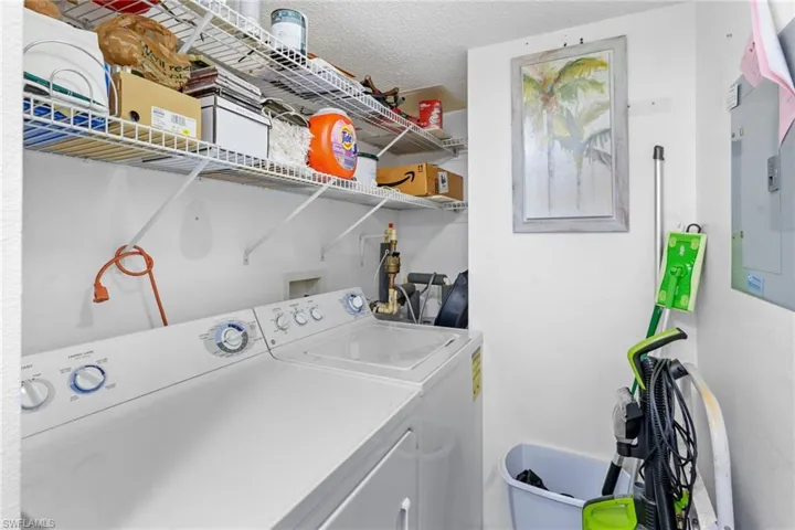 Washroom with electric panel, washing machine and dryer, and a textured ceiling