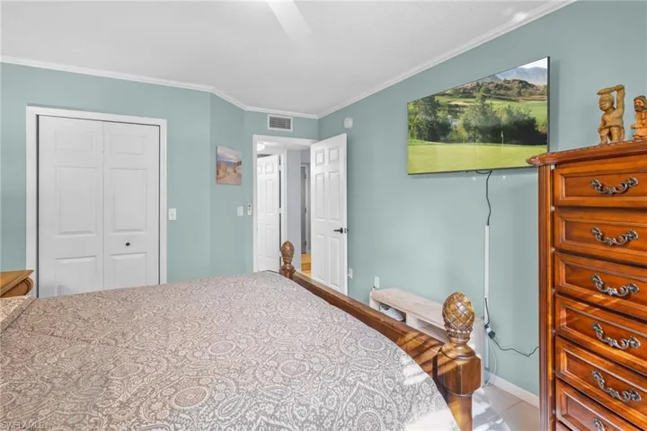 Bedroom with a closet, crown molding, ceiling fan, and light tile patterned flooring