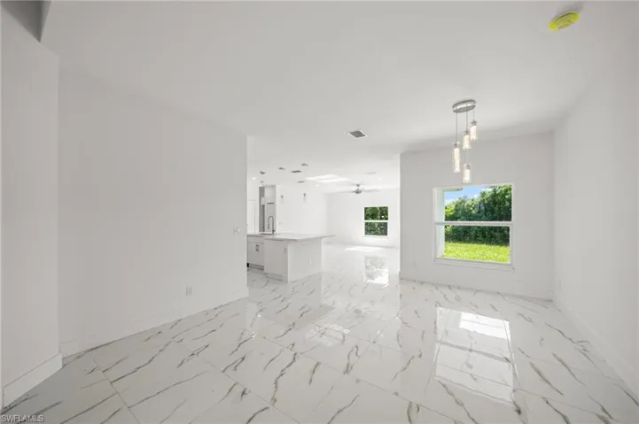 Empty room featuring light marble finish flooring and ceiling fan