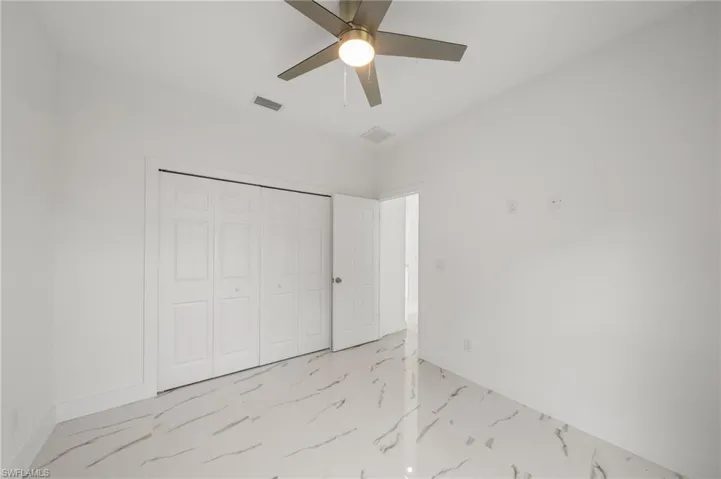 Spare room with light marble finish floors and ceiling fan