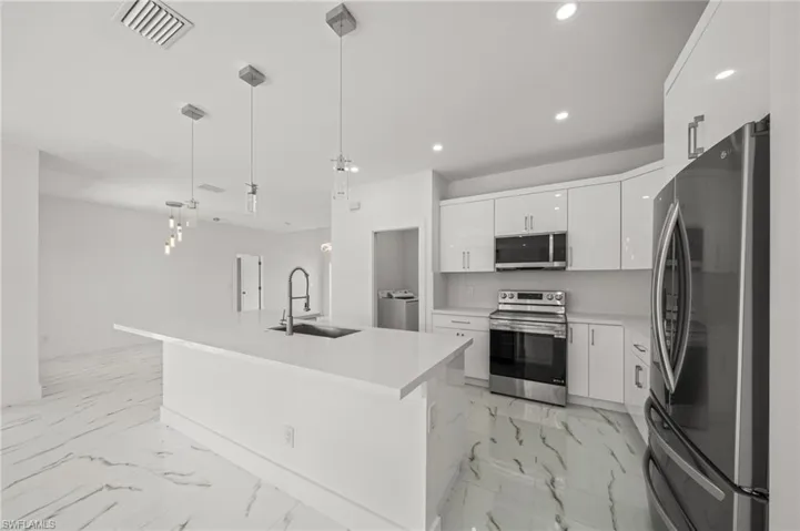 Kitchen with light marble finish floors, open floor plan, recessed lighting, stainless steel dishwasher, and white cabinets
