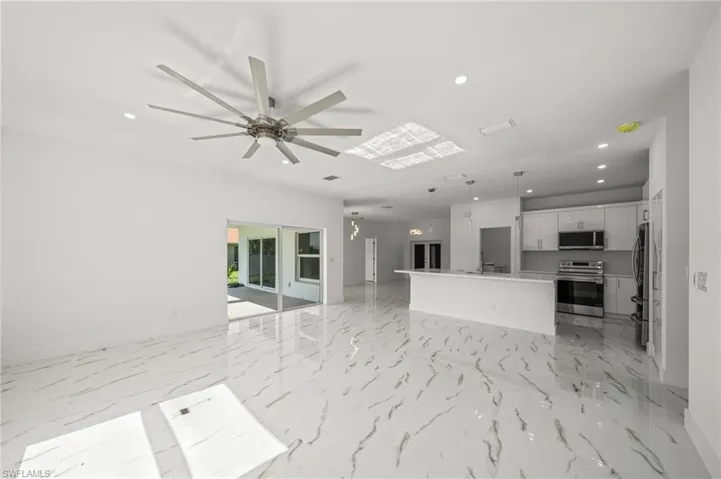 Kitchen featuring appliances with stainless steel finishes, white cabinets, light marble finish floors, modern cabinets, and washer / dryer