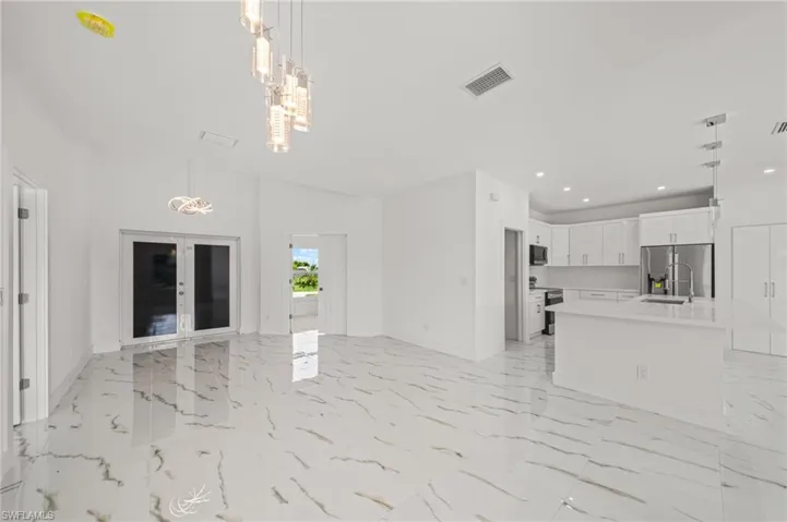 Kitchen featuring hanging light fixtures, stainless steel appliances, white cabinets, light marble finish flooring, and recessed lighting