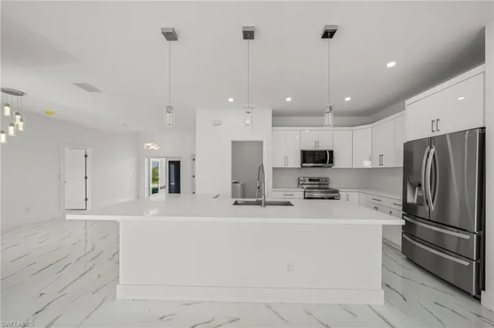 Kitchen featuring stainless steel appliances, white cabinetry, light marble finish floors, recessed lighting, and modern cabinets