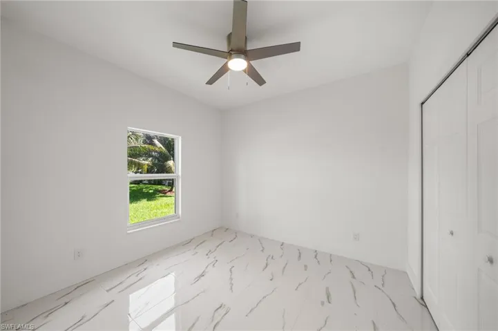 Spare room with light marble finish floors and ceiling fan