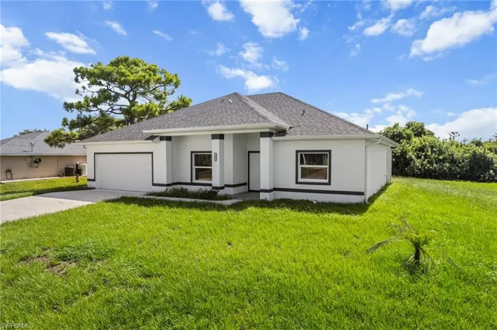 Rear view of house featuring stucco siding, a yard, roof with shingles, and a patio area