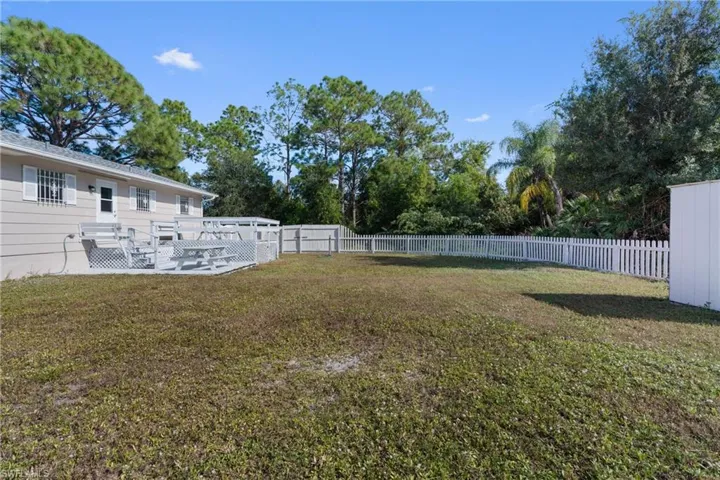 Fenced backyard with a patio and view of scattered trees