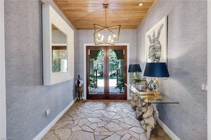 Entryway featuring a natural wood plank ceiling, a geometric chandelier, and flagstone flooring