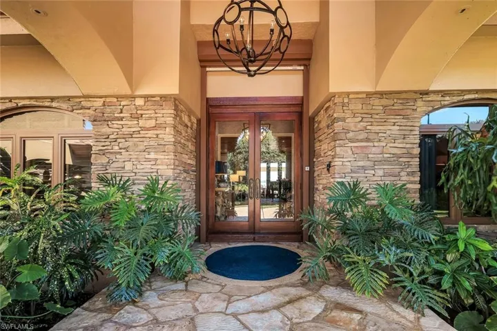 Stacked stone facade with arched entryways and a wood-frame double-door entrance featuring glass panels