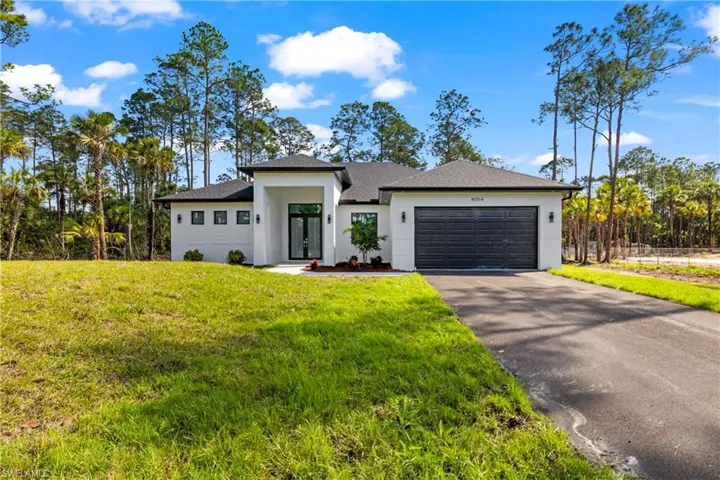 Prairie-style house with a front lawn, driveway, an attached garage, and stucco siding