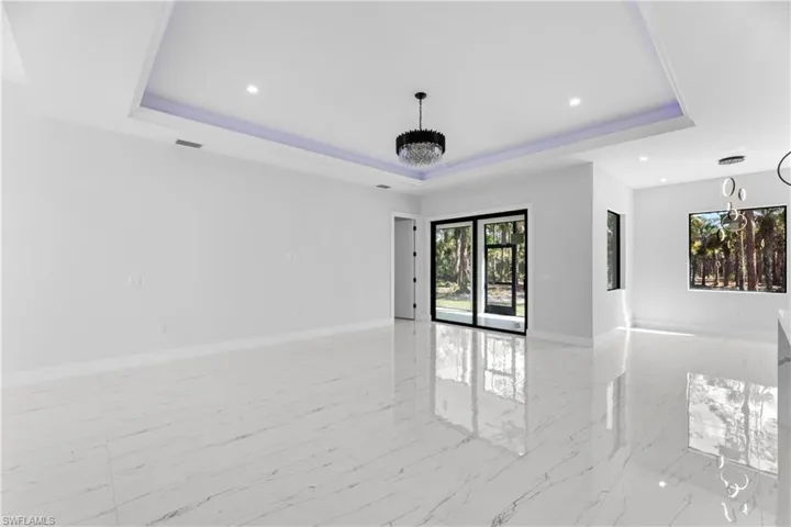 Spare room featuring visible vents, baseboards, a raised ceiling, a notable chandelier, and recessed lighting