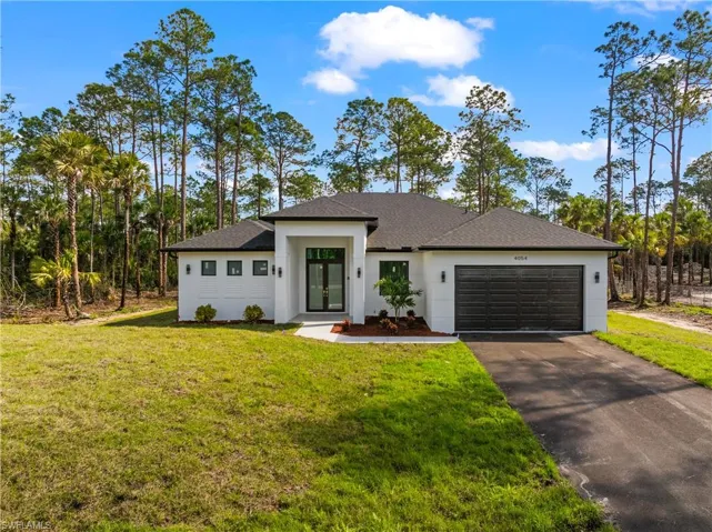 View of front facade with driveway, a front lawn, an attached garage, and stucco siding
