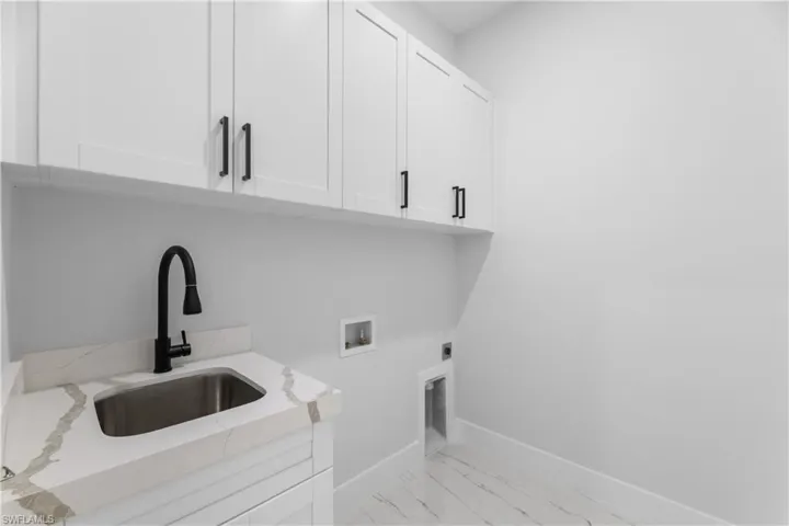 Washroom with cabinet space, baseboards, a sink, washer hookup, and electric dryer hookup