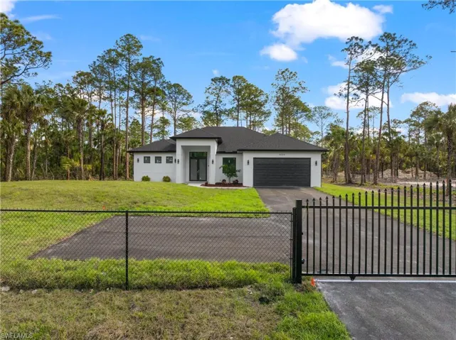 Prairie-style house with a garage, fence, driveway, stucco siding, and a front yard