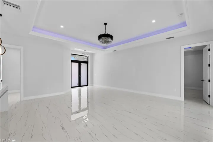 Spare room featuring a tray ceiling, visible vents, and baseboards
