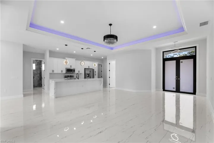 Unfurnished living room featuring french doors, a tray ceiling, and visible vents